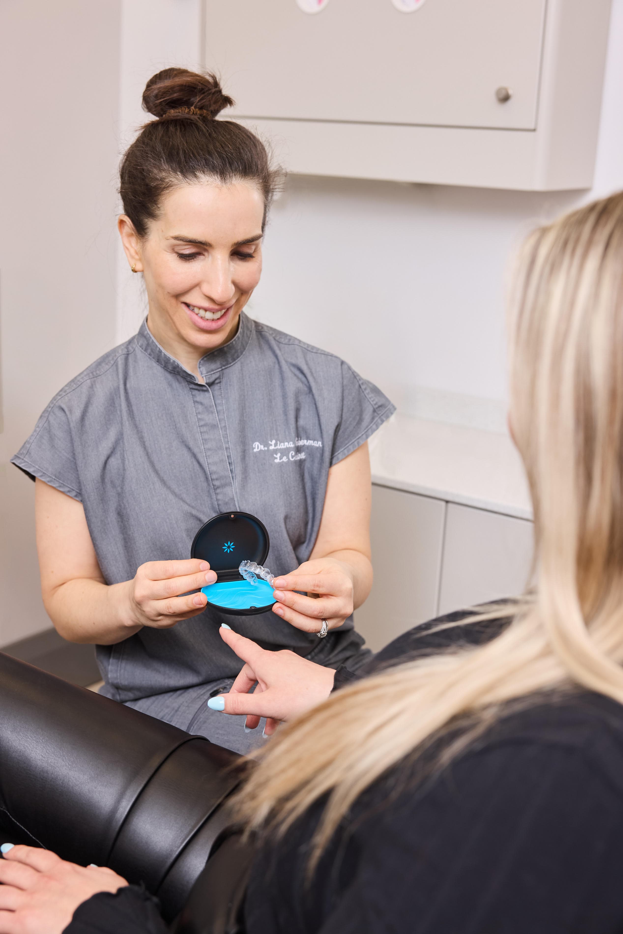 Dr. Liana Guberman showing a patient an Invisalign clear aligner